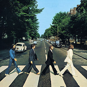 What is on the license plate on the back of the white VW Beetle that is behind George on the Abbey Road album cover?