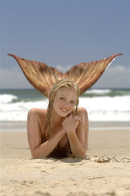 Rikki laying on the beach as a mermaid